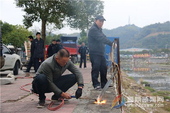 電焊工人在執(zhí)法人員的指導下，拆除人行道外的鐵柵欄，這些鐵柵欄為非法私建物品。.jpg